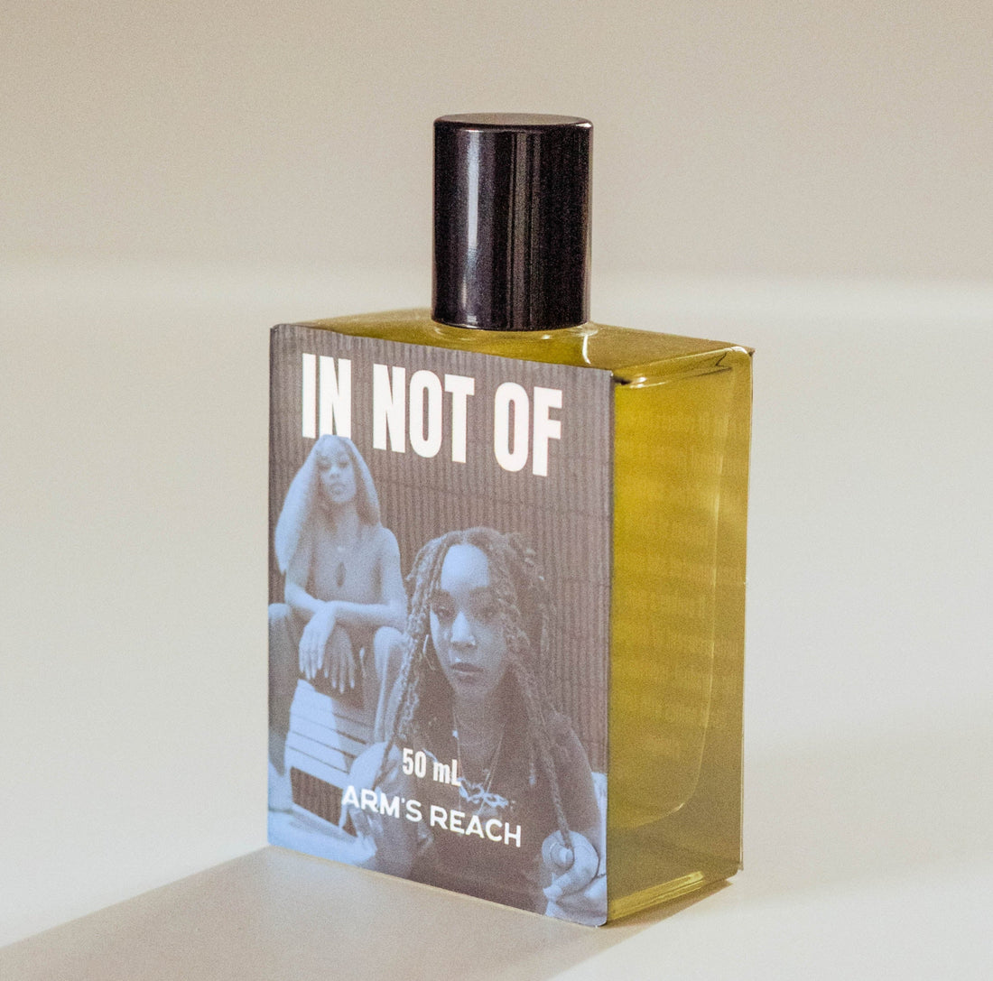 A 50ml bottle of Arm's Reach fragrance with a black cap and a label reading 'IN NOT OF', set against a plain beige background.